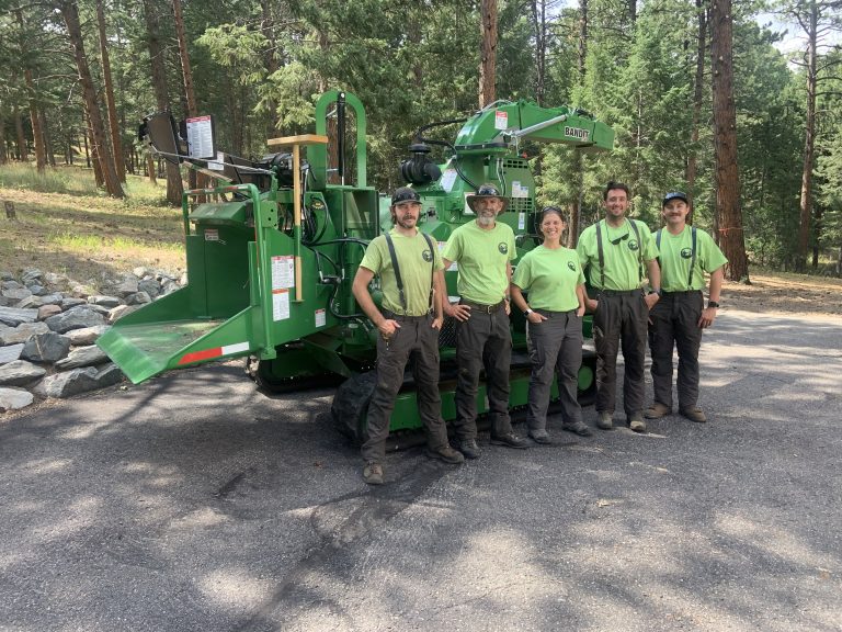 The All Things Vertical team standing in front of a Bandit tracked chipper.